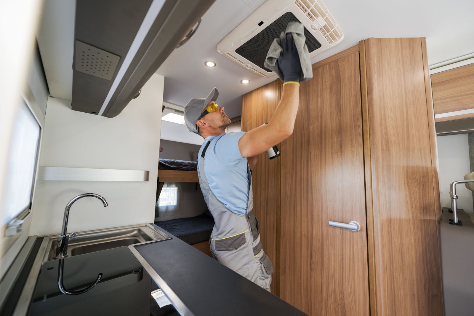 Man cleaning the interior of an RV and inspecting the AC system during winterization