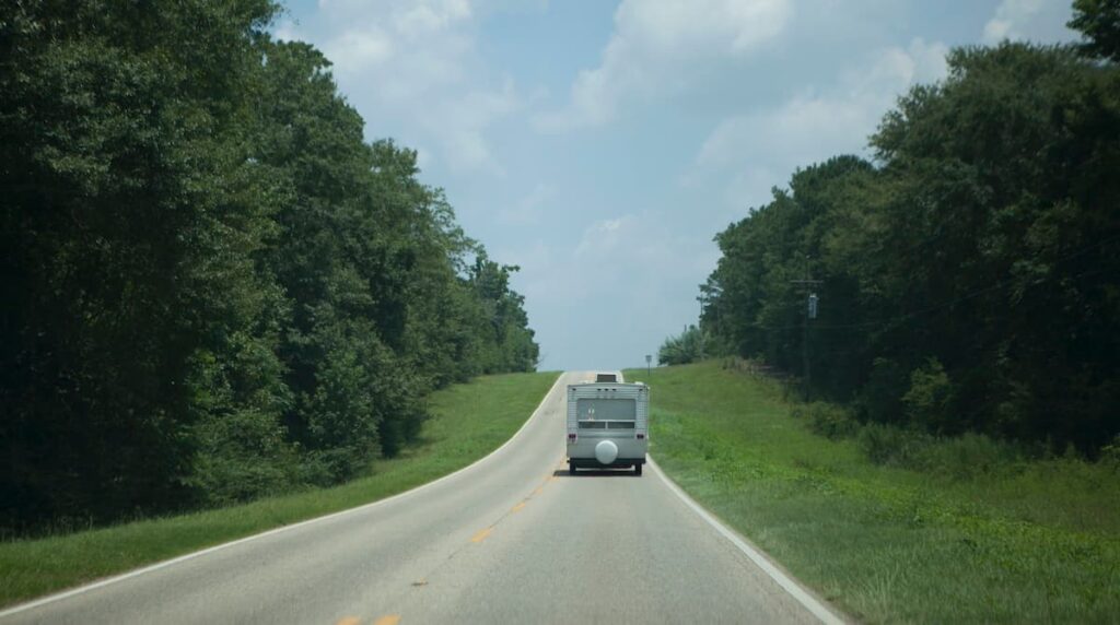 RV driving on Florida road on sunny day surrounded by green trees