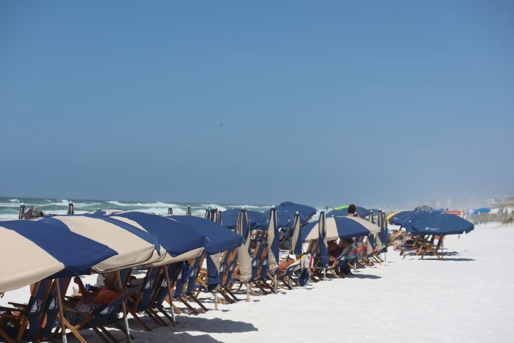 A line of blue and white beach umbrellas on a white sand beach in Destin, Florida