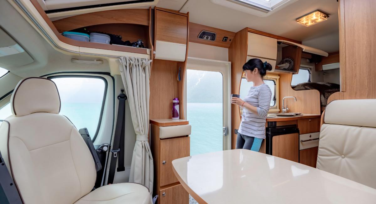 Interior view of luxury RV showing person using well-equipped galley kitchen with ample counter space and storage