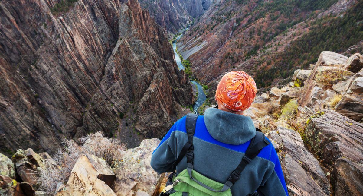 Hiker overlooking dramatic Black Canyon of the Gunnison National Park's steep dark cliffs and narrow gorge, 5 hours from Colorado Springs by RV