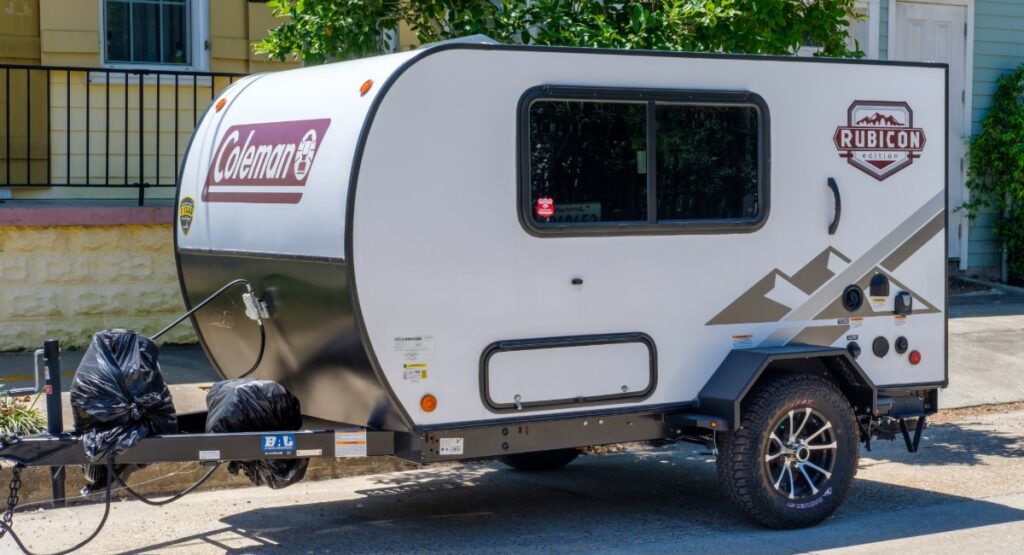 Coleman Rubicon lightweight travel trailer under 3000 pounds parked at campsite, compact RV rental perfect for couples' camping trips