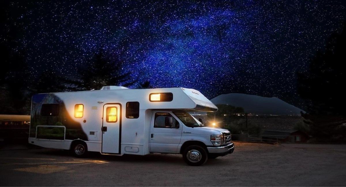 Class C motorhome parked at a campsite under a star-filled night sky